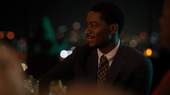 Movie still from “Snowfall” (2017), directed by Hiro Murai – A man sitting at a table in front of a city skyline; Close Up shot, High angle