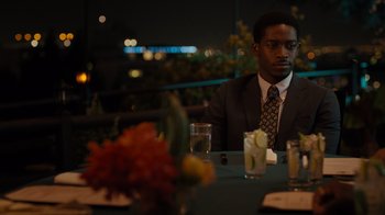 Movie still from “Snowfall” (2017), directed by Hiro Murai – A man sitting at a table with a drink in front of him; Medium shot, Over the shoulder angle