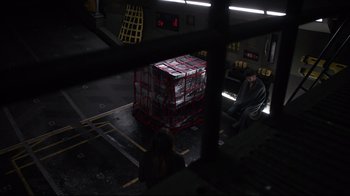 Movie still from “Agents of S.H.I.E.L.D.” (2013), created by Joss Whedon – A man sitting on a bench next to a large crate; Wide shot, High angle