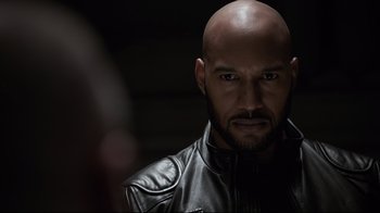 Movie still from “Agents of S.H.I.E.L.D.” (2013), created by Joss Whedon – A bald man in a leather jacket looking at the camera; Close Up shot, Over the shoulder angle