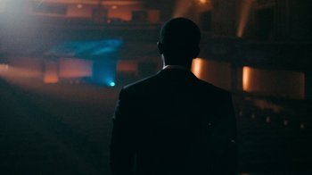 Movie still from “Snowfall” (2017), directed by Hiro Murai – A man in a suit standing in a dark room; Medium shot, Over the shoulder angle