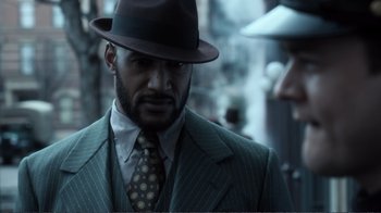 Movie still from “Agents of S.H.I.E.L.D.” (2013), created by Joss Whedon – A man wearing a suit and a hat; Close Up shot, Over the shoulder angle
