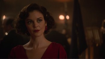 Movie still from “Agents of S.H.I.E.L.D.” (2013), created by Joss Whedon – A woman in a red dress is standing in a room; Close Up shot, Over the shoulder angle