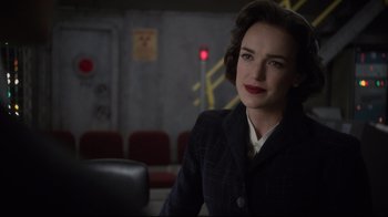 Movie still from “Agents of S.H.I.E.L.D.” (2013), created by Joss Whedon – A woman in a black jacket is sitting in a room; Close Up shot, Over the shoulder angle