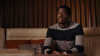 Movie still from “Snowfall” (2017), directed by Hiro Murai – A man sitting at a table in front of a glass of water; Close Up shot, Over the shoulder angle