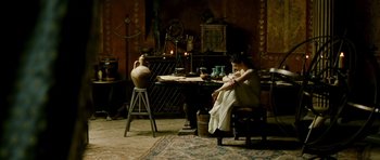 Movie still from “Agora” (2009), directed by Alejandro Amenábar – A woman sitting at a table in front of an antique clock; Wide shot, High angle