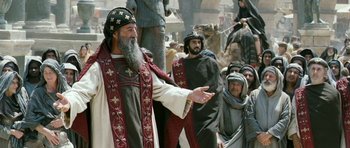 Movie still from “Agora” (2009), directed by Alejandro Amenábar – An old man wearing a red and white robe and a black hat; Medium shot, Low angle