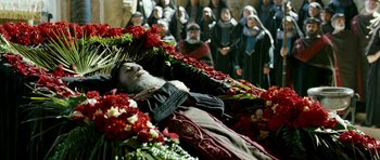 Movie still from “Agora” (2009), directed by Alejandro Amenábar – An old man laying on a bed of flowers; Wide shot, Overhead angle