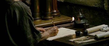 Movie still from “Agora” (2009), directed by Alejandro Amenábar – An old man writing on a piece of paper by a candle; Close Up shot, High angle