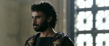 Movie still from “Agora” (2009), directed by Alejandro Amenábar – A man with a beard wearing a black and red shirt; Close Up shot, Over the shoulder angle