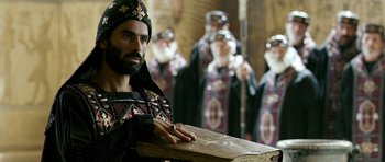 Movie still from “Agora” (2009), directed by Alejandro Amenábar – A man holding an open bible in front of a group of men; Medium shot, Over the shoulder angle
