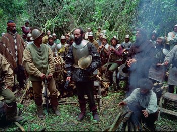 Movie still from “Aguirre, the Wrath of God” (1972), directed by Werner Herzog – A group of men in medieval garb gathered in the woods; Wide shot, High angle