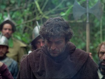 Movie still from “Aguirre, the Wrath of God” (1972), directed by Werner Herzog – A man in a brown robe is looking down at his face; Close Up shot, Over the shoulder angle