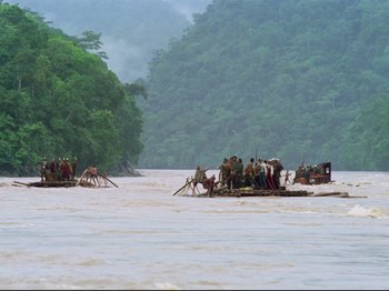 Movie still from “Aguirre, the Wrath of God” (1972), directed by Werner Herzog – A group of people on a raft in a body of water; Extreme Wide shot, High angle