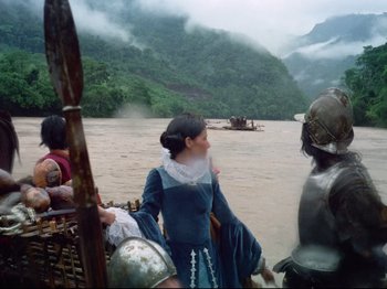 Movie still from “Aguirre, the Wrath of God” (1972), directed by Werner Herzog – A woman dressed as a medieval princess on a river; Wide shot, Over the shoulder angle