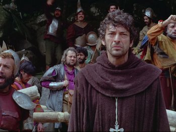 Movie still from “Aguirre, the Wrath of God” (1972), directed by Werner Herzog – A group of men in medieval garb standing in front of a crowd; Medium shot, Low angle