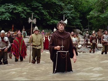 Movie still from “Aguirre, the Wrath of God” (1972), directed by Werner Herzog – A group of people walking through a body of water; Wide shot, High angle