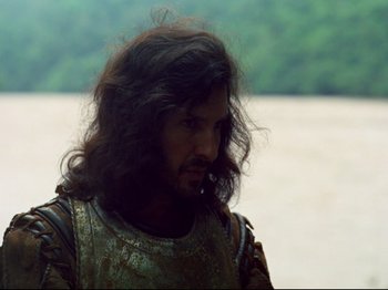 Movie still from “Aguirre, the Wrath of God” (1972), directed by Werner Herzog – A person with long curly hair; Close Up shot, Over the shoulder angle