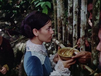 Movie still from “Aguirre, the Wrath of God” (1972), directed by Werner Herzog – A woman in a blue dress is holding a bowl of bananas; Medium shot, Low angle
