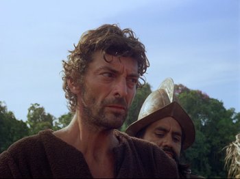 Movie still from “Aguirre, the Wrath of God” (1972), directed by Werner Herzog – A man with a beard and a hat is standing next to another man with a beard; Close Up shot, Low angle