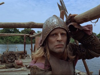 Movie still from “Aguirre, the Wrath of God” (1972), directed by Werner Herzog – A man wearing a helmet and holding a spear; Medium shot, Low angle