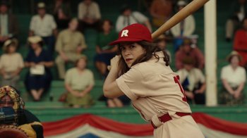 Movie still from “A League of Their Own” (2022), created by Abbi Jacobson – A woman in a baseball uniform holding a baseball bat; Medium shot, Over the shoulder angle