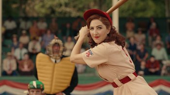 Movie still from “A League of Their Own” (2022), created by Abbi Jacobson – A woman in a baseball uniform holding a baseball bat; Medium shot, Over the shoulder angle
