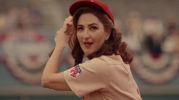 Movie still from “A League of Their Own” (2022), created by Abbi Jacobson – A woman in a baseball uniform holding a hat; Close Up shot, Over the shoulder angle