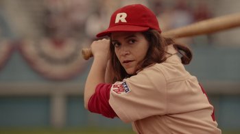 Movie still from “A League of Their Own” (2022), created by Abbi Jacobson – A female baseball player is holding a baseball bat; Close Up shot, Over the shoulder angle