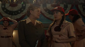 Movie still from “A League of Their Own” (2022), created by Abbi Jacobson – Two women standing next to each other in front of an american flag; Medium shot, Over the shoulder angle