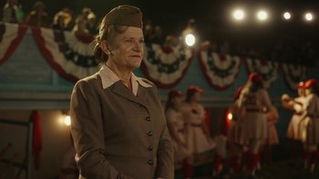 Movie still from “A League of Their Own” (2022), created by Abbi Jacobson – An older woman in a brown suit and hat; Medium shot, Low angle