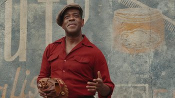 Movie still from “A League of Their Own” (2022), created by Abbi Jacobson – A man in a red shirt holding a baseball glove; Close Up shot, Low angle