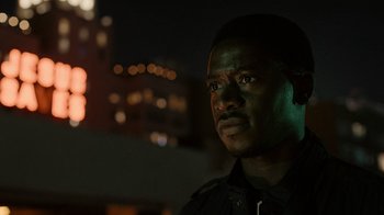 Movie still from “Snowfall” (2017), directed by Hiro Murai – A man in a black shirt is looking at the camera; Close Up shot, Low angle