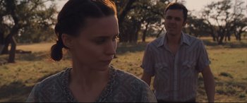 Movie still from “Ain't Them Bodies Saints” (2013), directed by David Lowery – A man and a woman standing in a field; Close Up shot, Over the shoulder angle