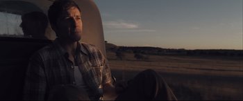 Movie still from “Ain't Them Bodies Saints” (2013), directed by David Lowery – A man sitting in the back seat of a car; Medium shot, Low angle