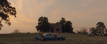 Movie still from “Ain't Them Bodies Saints” (2013), directed by David Lowery – A couple of people sitting on the hood of a car; Extreme Wide shot, Low angle