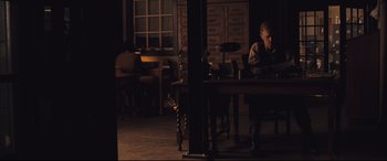 Movie still from “Ain't Them Bodies Saints” (2013), directed by David Lowery – A man sitting at a table in a dark room; Wide shot, High angle