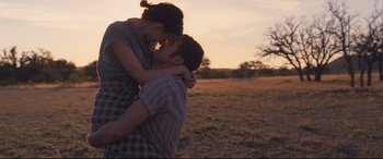 Movie still from “Ain't Them Bodies Saints” (2013), directed by David Lowery – A man and a woman kissing in a field at sunset; Medium shot, High angle