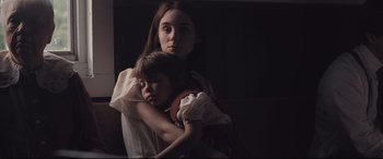 Movie still from “Ain't Them Bodies Saints” (2013), directed by David Lowery – A woman holding a child in her arms in a dark room; Close Up shot, Low angle