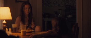 Movie still from “Ain't Them Bodies Saints” (2013), directed by David Lowery – A girl sitting at a dinner table with a plate of food in front of her; Medium shot, Over the shoulder angle