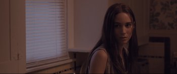 Movie still from “Ain't Them Bodies Saints” (2013), directed by David Lowery – A woman standing next to a window in a room; Close Up shot, Over the shoulder angle