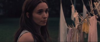 Movie still from “Ain't Them Bodies Saints” (2013), directed by David Lowery – A young woman is standing in front of a clothes line; Close Up shot, Over the shoulder angle