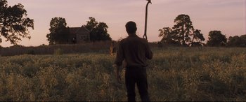 Movie still from “Ain't Them Bodies Saints” (2013), directed by David Lowery – A man standing in a field holding a pole; Wide shot, Low angle
