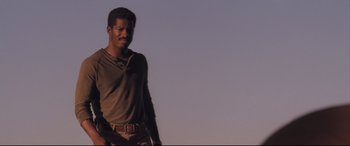 Movie still from “Ain't Them Bodies Saints” (2013), directed by David Lowery – A man standing in the middle of a field; Medium shot, Low angle