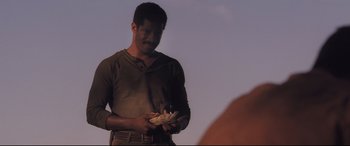 Movie still from “Ain't Them Bodies Saints” (2013), directed by David Lowery – A man is holding something in his hands; Medium shot, Low angle