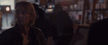 Movie still from “Ain't Them Bodies Saints” (2013), directed by David Lowery – A person is sitting in a dark room with other people; Close Up shot, Over the shoulder angle