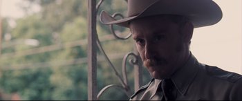 Movie still from “Ain't Them Bodies Saints” (2013), directed by David Lowery – A man with a mustache wearing a cowboy hat; Close Up shot, Over the shoulder angle
