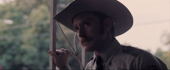 Movie still from “Ain't Them Bodies Saints” (2013), directed by David Lowery – A man in a cowboy hat is looking at the camera; Close Up shot, Over the shoulder angle