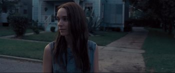 Movie still from “Ain't Them Bodies Saints” (2013), directed by David Lowery – A woman with long brown hair standing in front of a house; Close Up shot, Over the shoulder angle