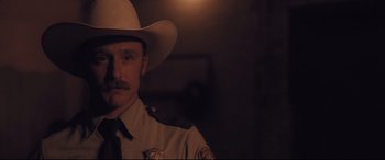 Movie still from “Ain't Them Bodies Saints” (2013), directed by David Lowery – A man wearing a hat and a uniform; Close Up shot, Over the shoulder angle